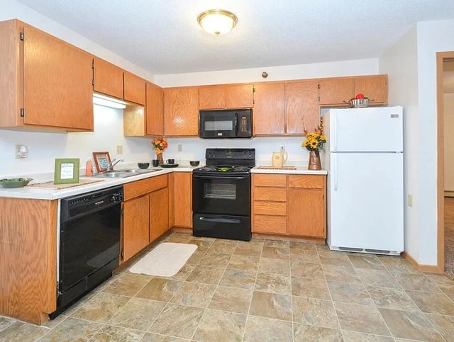 Kitchen with wooden cabinets, black appliances, and tiled floor.