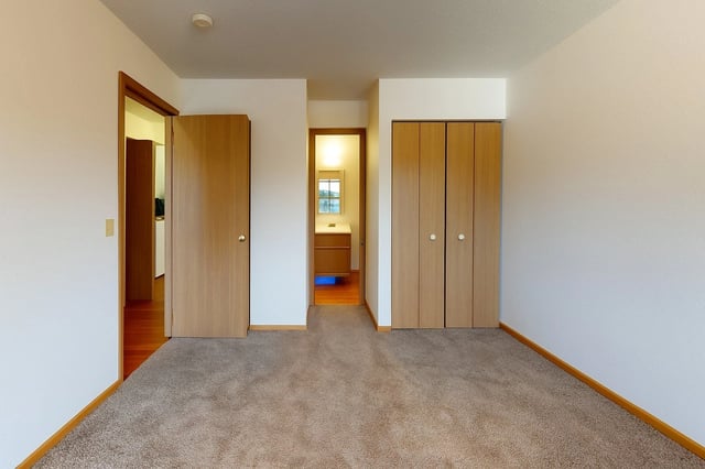 Bedroom with two closets and doorway to bathroom.