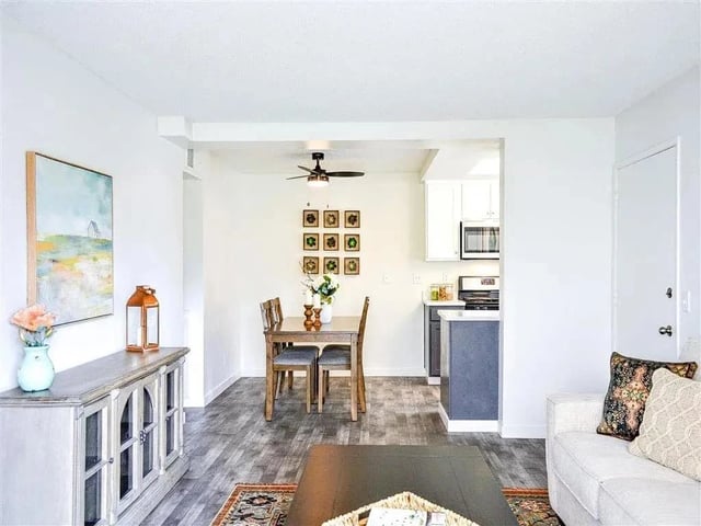 Living and dining area adjacent to kitchen in apartment.