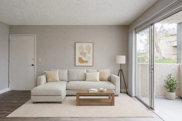 Modern living room with a sectional sofa, coffee table, floor lamp, and a large sliding glass door leading to a balcony.