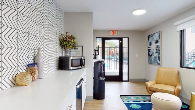 Kitchenette area with microwave, snacks, and a water cooler, leading to an outdoor pool area.