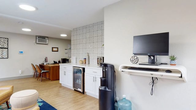 Community area with computer desk, water cooler, and mini fridge.