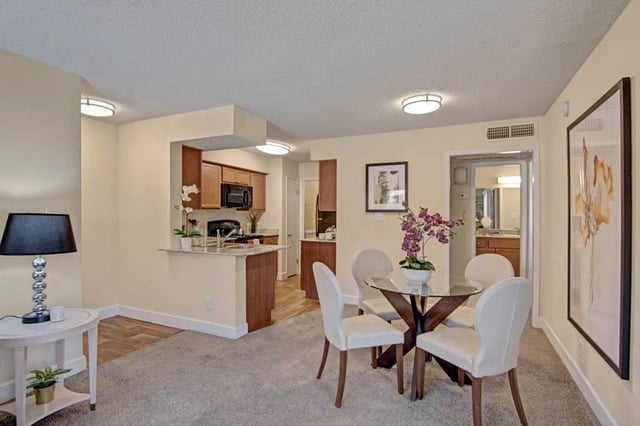 Modern dining area and open kitchen with wooden cabinets and granite countertops.