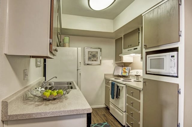 Kitchen with white cabinets, a refrigerator, microwave, oven, and sink.