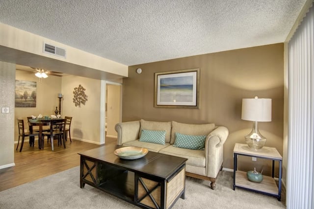 Living room with sofa, coffee table, and dining area visible.