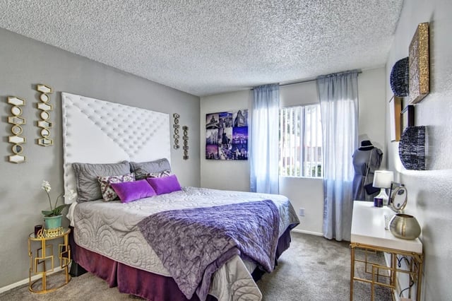 Bedroom with a king-size bed, purple accents, and wall decor.