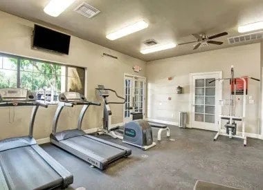 Fitness center with treadmills, elliptical, weight machine, and bench.