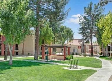 Apartment complex grounds with outdoor grilling area and grassy courtyard.