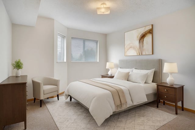 A beautifully staged bedroom with a queen-size bed, nightstands, and a cozy armchair.