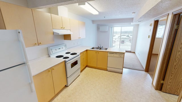 Kitchen with white appliances, light wood cabinets, and a view of the outdoors.