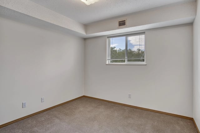 Empty room with neutral walls, carpet, and a window with blinds.
