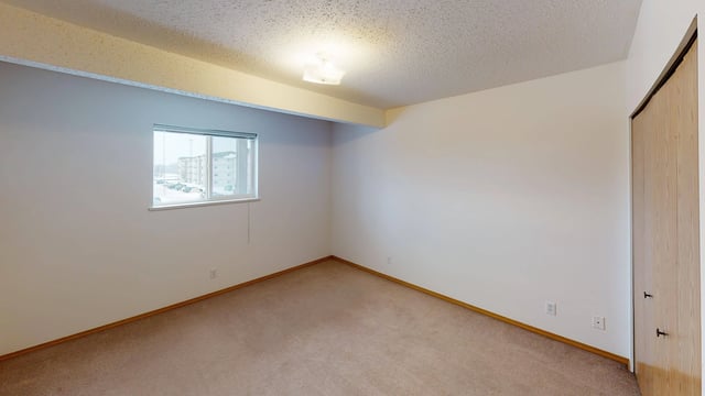 Empty bedroom with a large window and a closet.