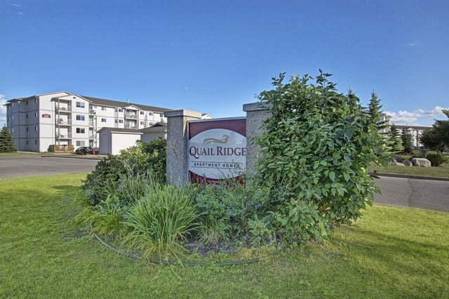 Quail Ridge Apartment Homes monument sign and building exterior on a sunny day.