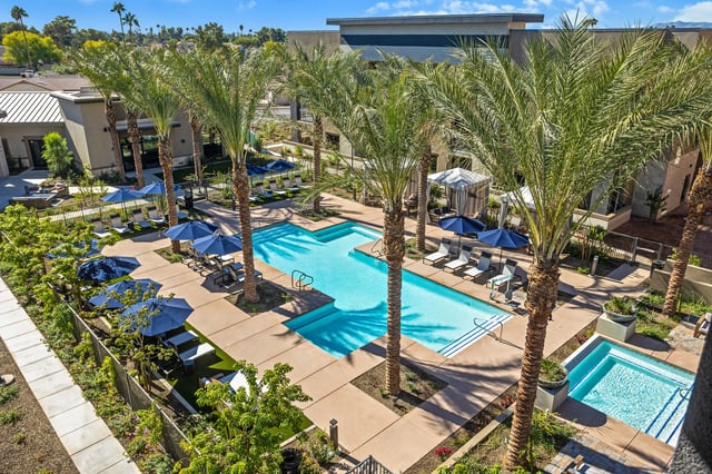 Outdoor swimming pool and hot tub area with lounge chairs and umbrellas