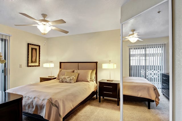 Bedroom with a queen-size bed, nightstands, lamps, and ceiling fan.