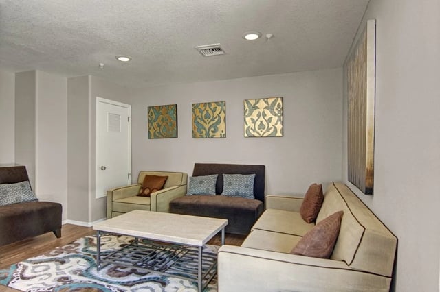 Living room with sofa, armchairs, coffee table, and decorative wall art.