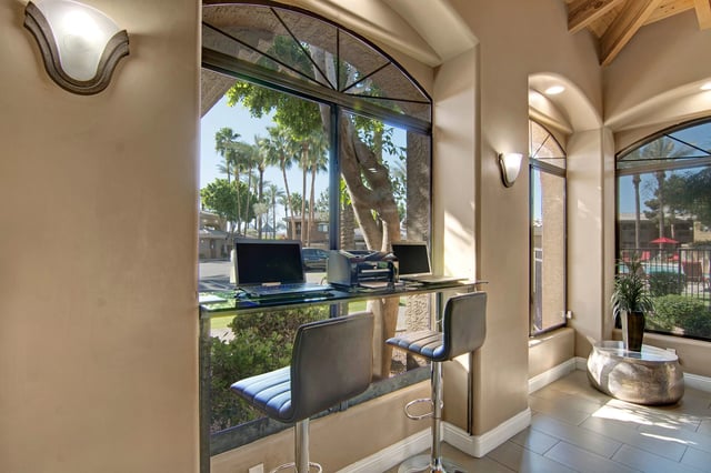 Business center with laptops and printer with view of pool and palm trees.