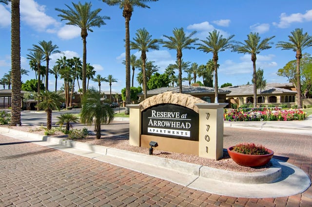 Reserve at Arrowhead Apartments monument sign with palm trees and flowers.