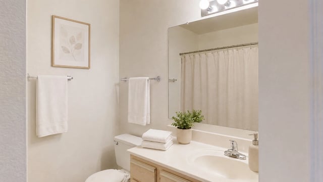 Bathroom with a vanity, sink, toilet, mirror, and shower with a curtain.