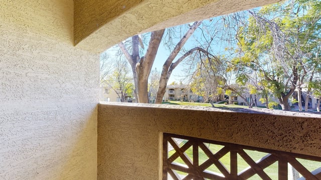 View of apartment buildings and trees from a balcony with textured walls.