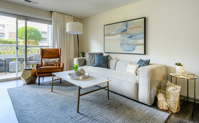 Modern living room with a sofa, accent chair, coffee table, and balcony access.