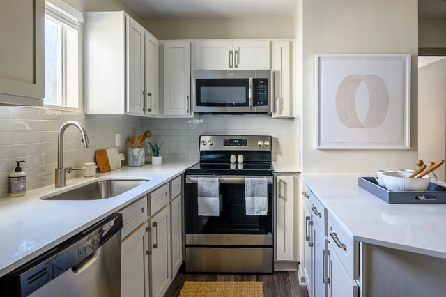 Modern kitchen with white cabinets, stainless steel appliances, and quartz countertops.