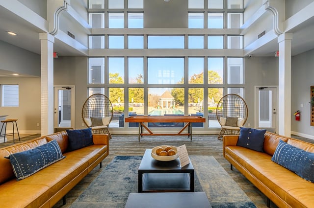 Stylish lounge area with leather sofas, egg chairs, and a shuffleboard table overlooking an outdoor pool.