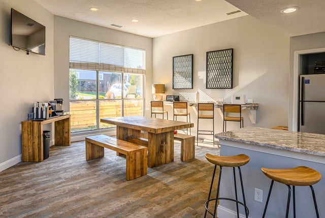 Community room with coffee station, communal table, and bar seating.