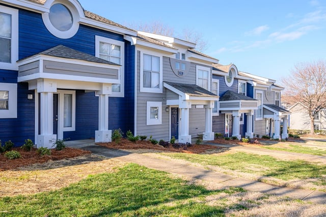 Exterior of blue and gray townhomes with white trim and covered entrances.
