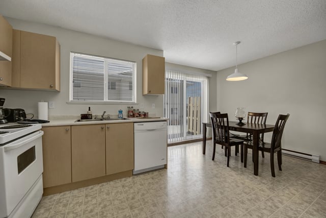 Kitchen and dining area with white appliances and a dark wood dining set.