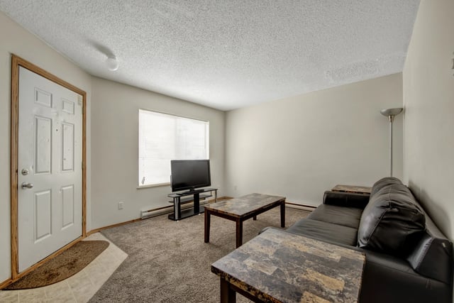 Living room with a black leather sofa, two coffee tables, and a television.