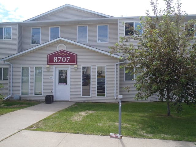 Building exterior with address 8707 and a small tree.