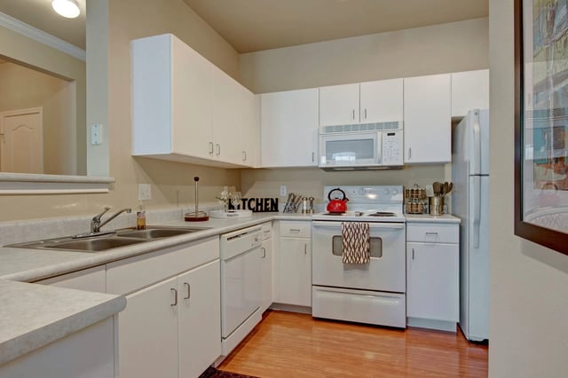 Kitchen with white cabinets, stainless steel sink, white stove, and refrigerator.