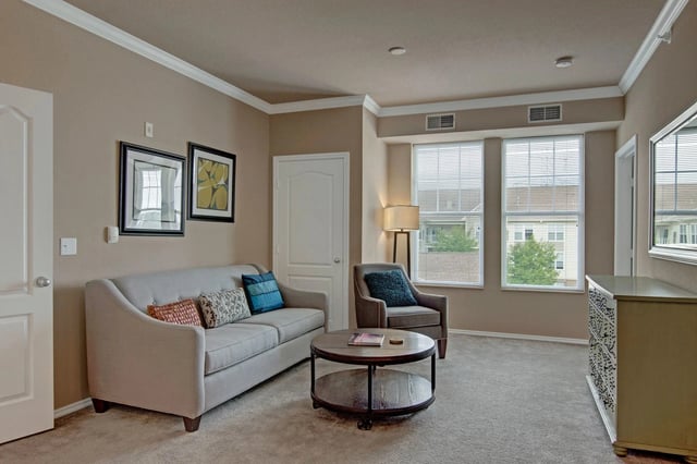 Living room with sofa, armchair, coffee table, and dresser.