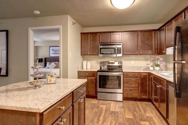 Modern kitchen with stainless steel appliances and island, view into bedroom.