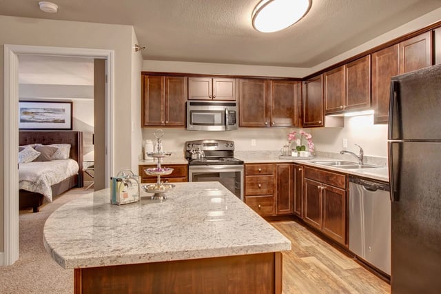 Modern kitchen with granite countertops and stainless steel appliances, view of bedroom beyond.