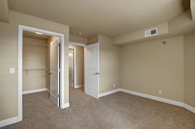 Empty bedroom with a closet and two doors.