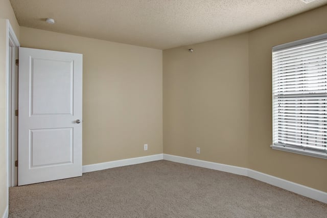 Empty room with a closed door and blinds on the window.