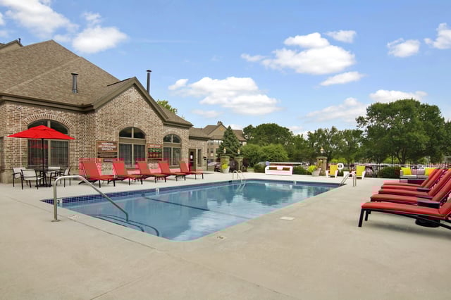Resort-style outdoor swimming pool with lounge chairs and umbrellas.