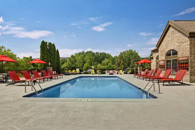 Resort-style swimming pool with red lounge chairs and umbrellas.