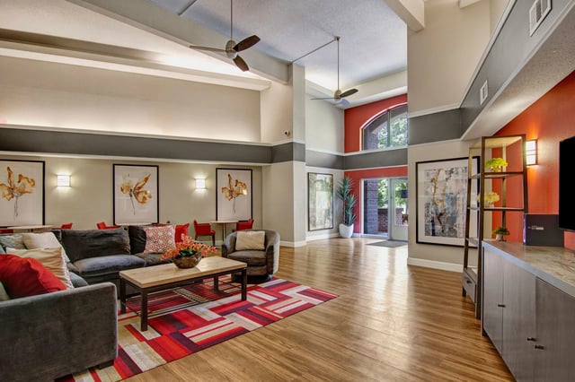 Spacious apartment complex lobby with modern furniture, large artwork, and high ceilings.