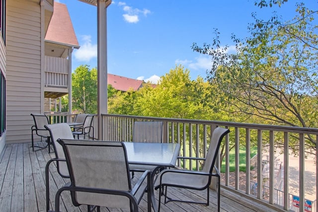 Balcony with table and chairs overlooking trees and buildings.
