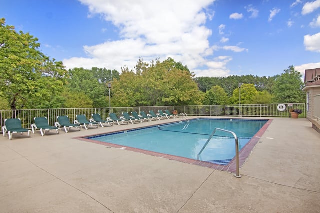 Outdoor swimming pool with lounge chairs and trees.