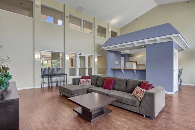 Community lounge with large sectional sofa, coffee table, and bar area.