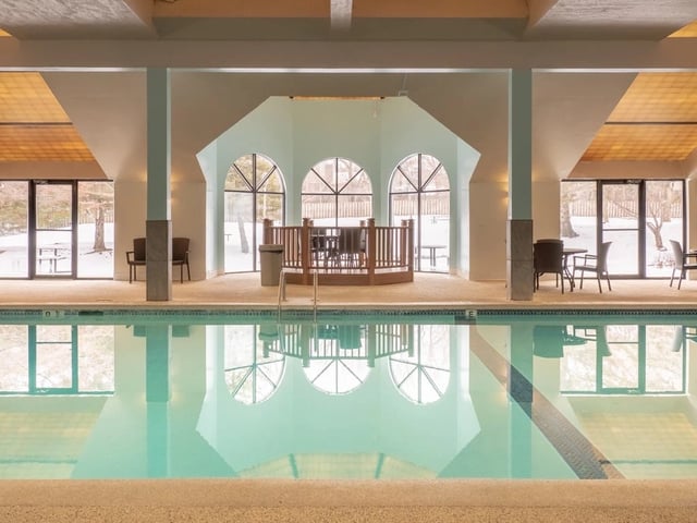 Indoor swimming pool with reflection of arched windows and surrounding seating area.