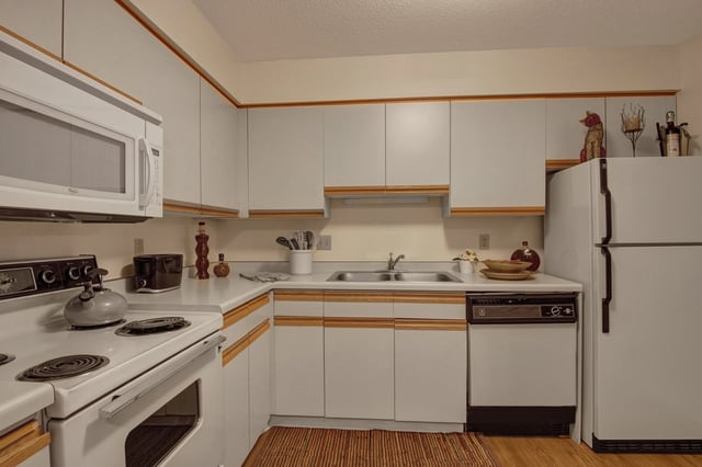 Kitchen with white countertops, white cabinets, stainless steel appliances including a microwave, oven, dishwasher, and refrigerator.