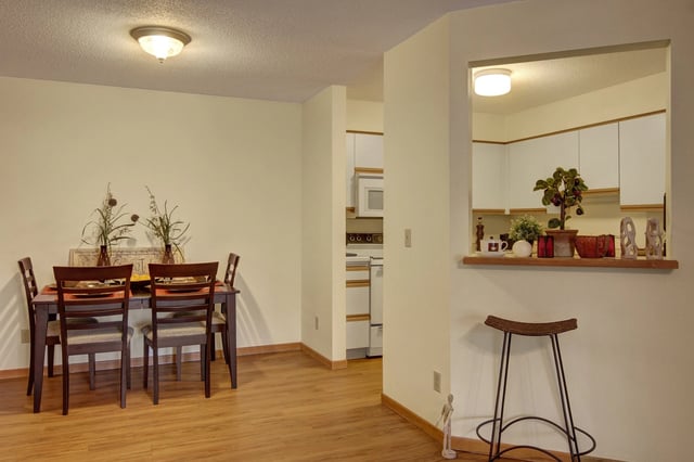 Dining area with a table and chairs, open to the kitchen with a breakfast bar and stools.
