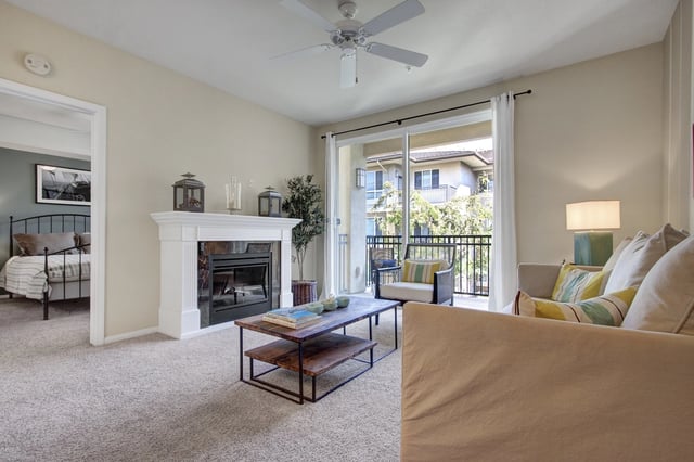 Living room with fireplace, coffee table, and bedroom visible through doorway.