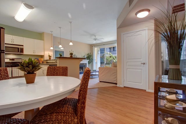 Dining area with white table and chairs, leading to kitchen and living room.