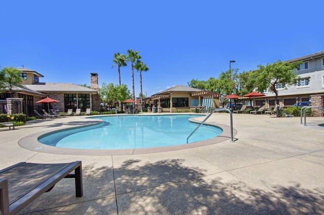 Resort-style swimming pool with lounge chairs and umbrellas at a multifamily property.